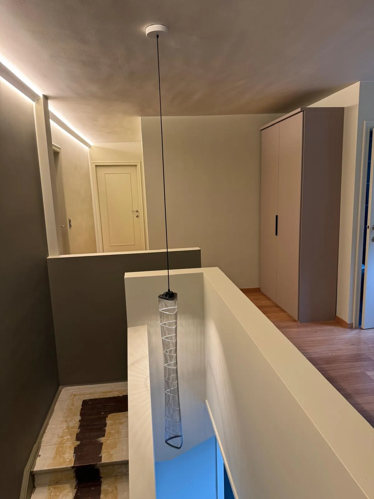Overloop met dezelfde design-hanglamp en inbouwkast, LED-lijnverlichting zichtbaar op de achtergrond