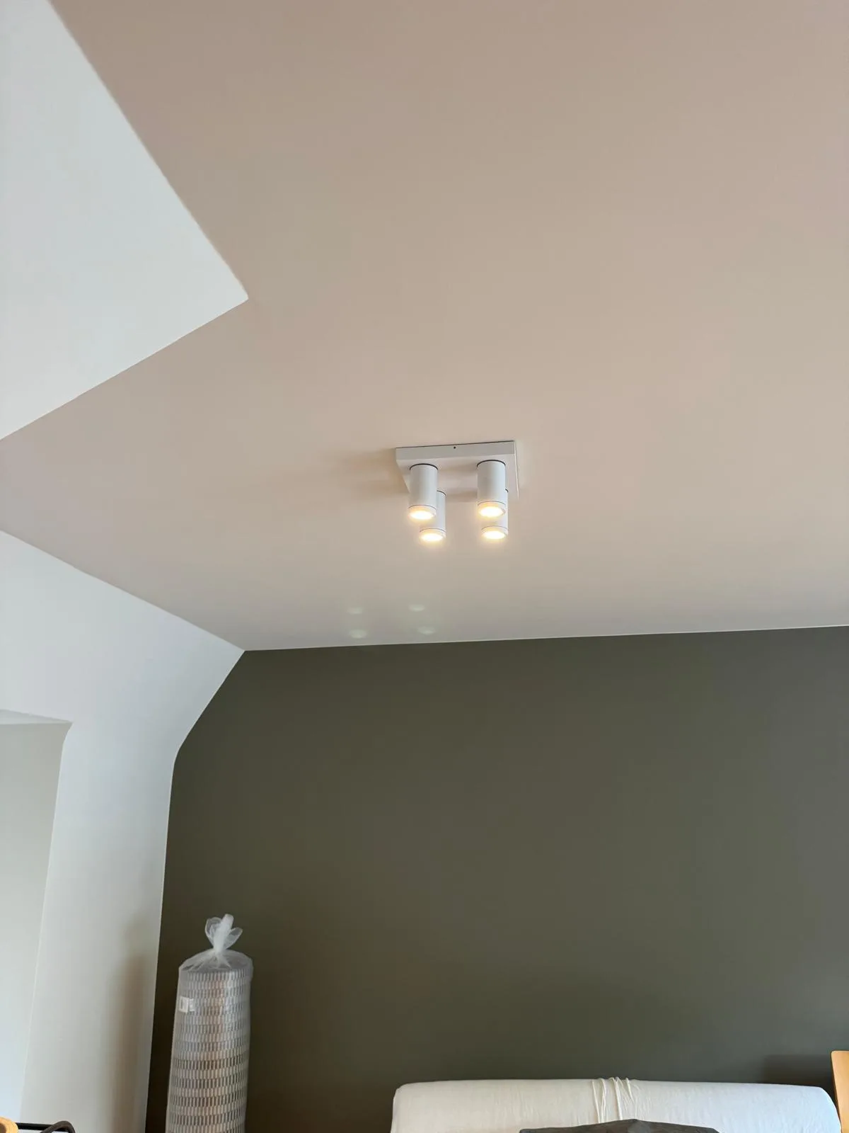 Vierkante opbouwspot met vier LED-spots op het plafond boven een donkergroene muur